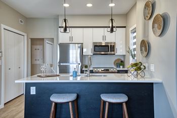 A modern kitchen with a blue backsplash and white countertops.